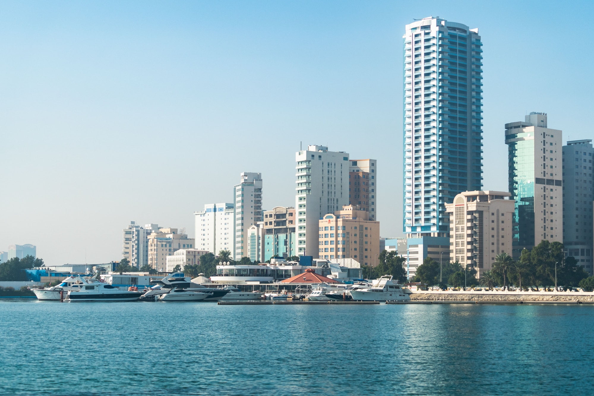 Manama skyline from Persian Gulf against blue sky background in Bahrain